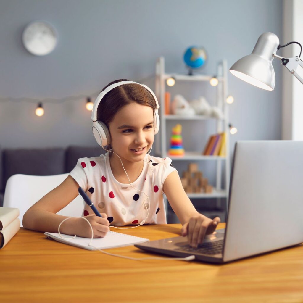 little girl working on laptop with headphones on