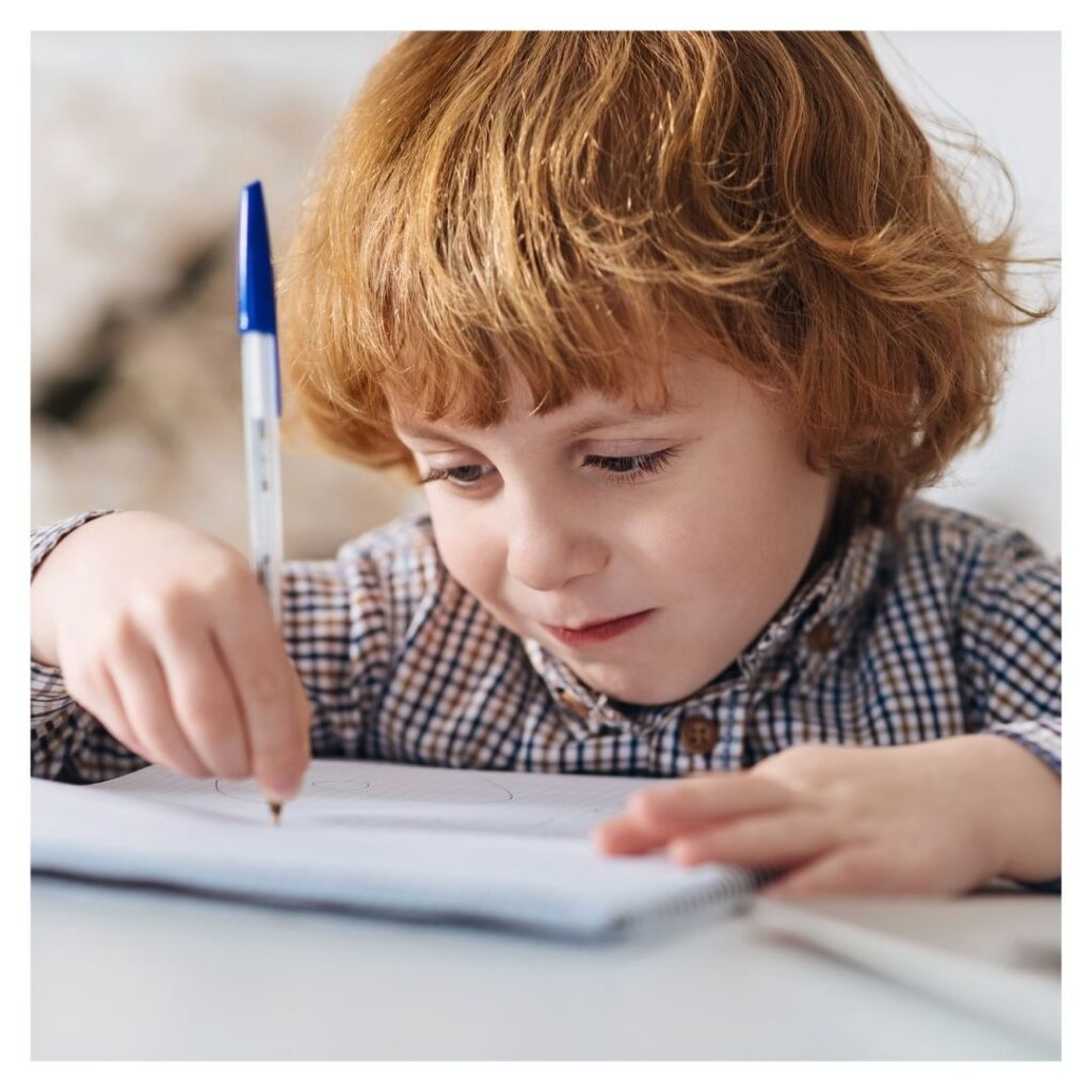 little red headed boy writing on paper