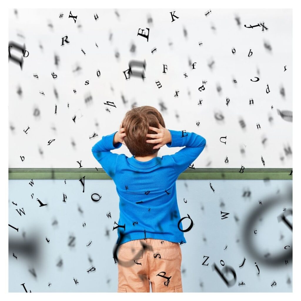 little boy clutching ears with letters floating around him